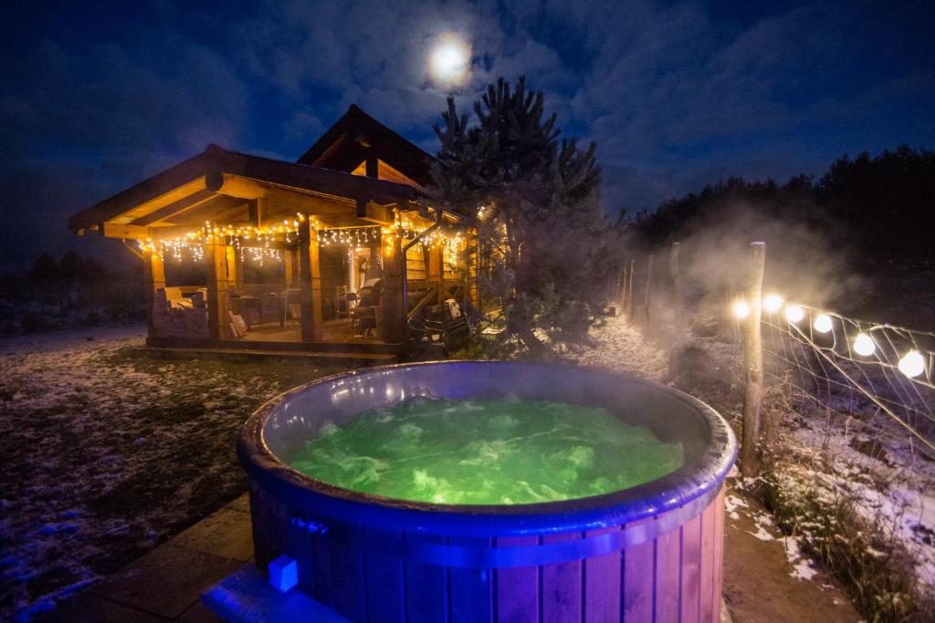 a hot tub in front of a log cabin at night at Dom z bala Sosnowy in Mrągowo