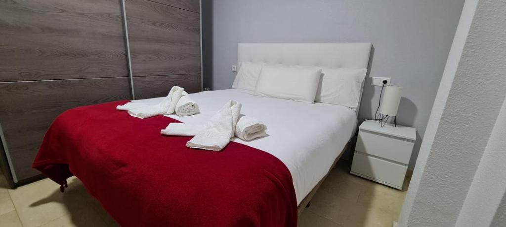 a bed with white socks and shoes on a red blanket at Casa Puerta de la Victoria in Córdoba