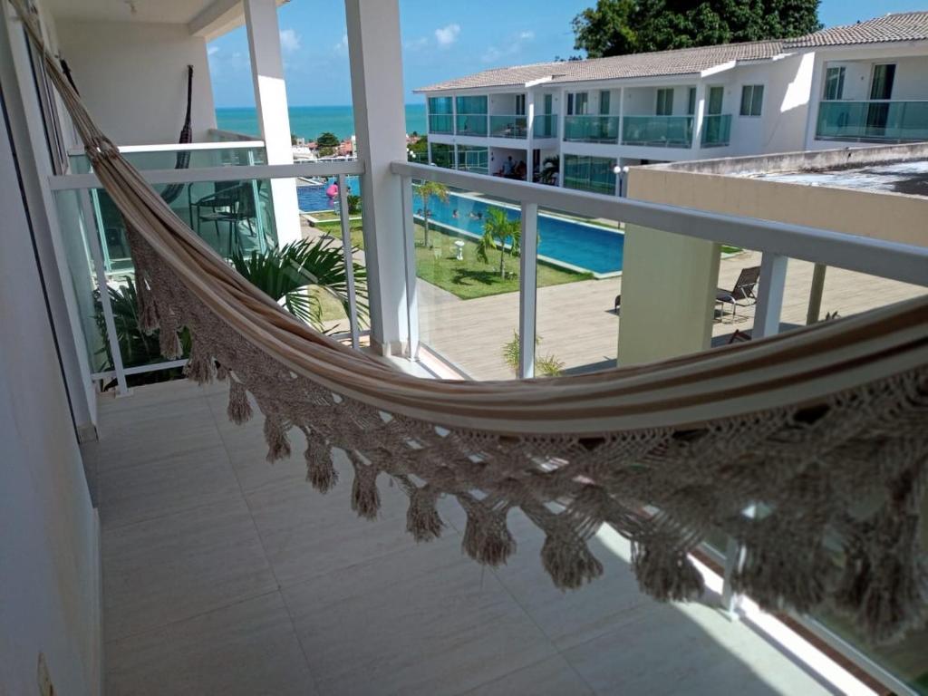 a hammock on a balcony with a view of the ocean at Duplex Paraíba Litoral Sul Jacumã Acesso as Melhores Praias do Brasil in Jacumã