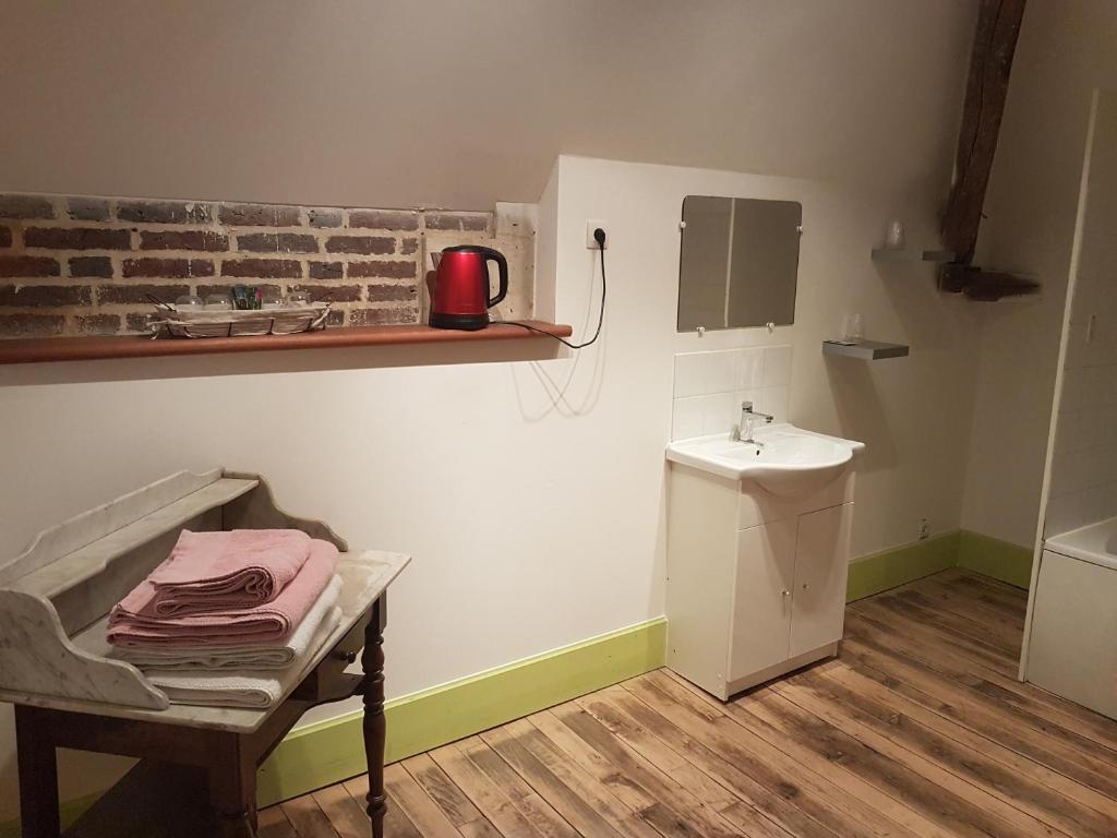 a bathroom with a sink and a table with a chair at Le Betrot in Estissac