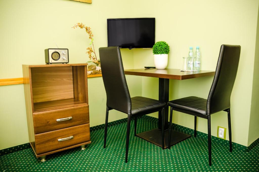 a desk with two chairs and a table with a dresser at Doby Hotelowe in Zgorzelec