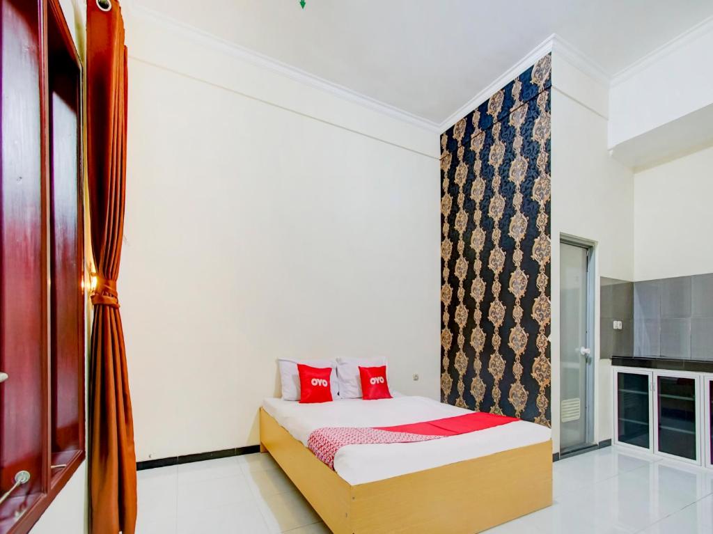 a bedroom with a bed with red pillows and a window at Super Capital O 90151 Guest House 180 in Batu
