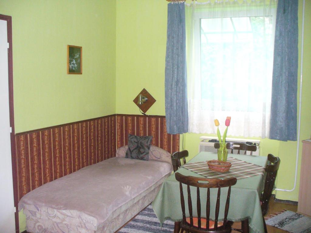 1 dormitorio con cama, mesa y ventana en Pleiveisz Apartman, en Sárvár