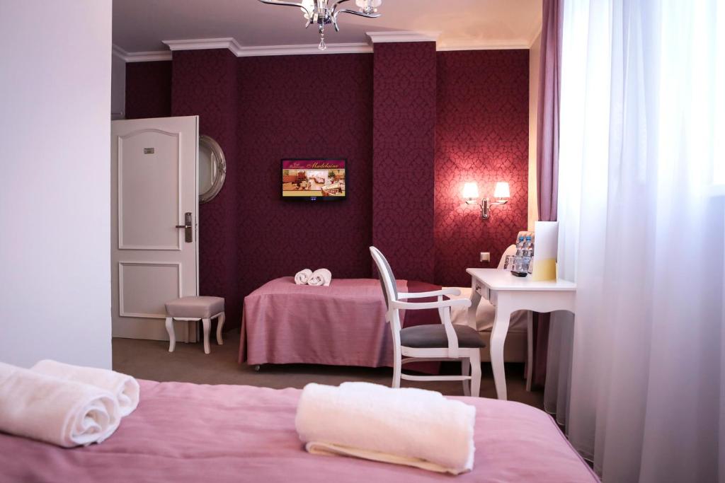 1 Schlafzimmer mit 2 Betten, einem Tisch, einem Tisch und Stühlen in der Unterkunft Hotel Madelaine in Lwówek Śląski