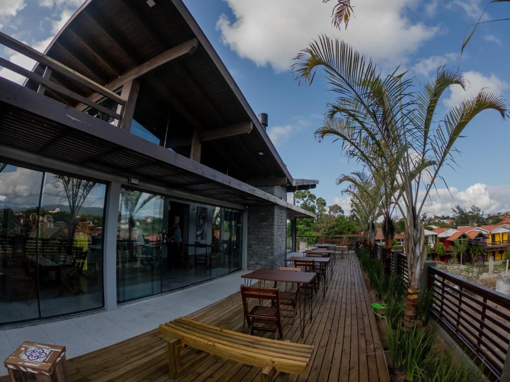 un restaurante con terraza de madera con mesas y bancos en Pousada Cabanas Kaia Lua, en Praia do Rosa