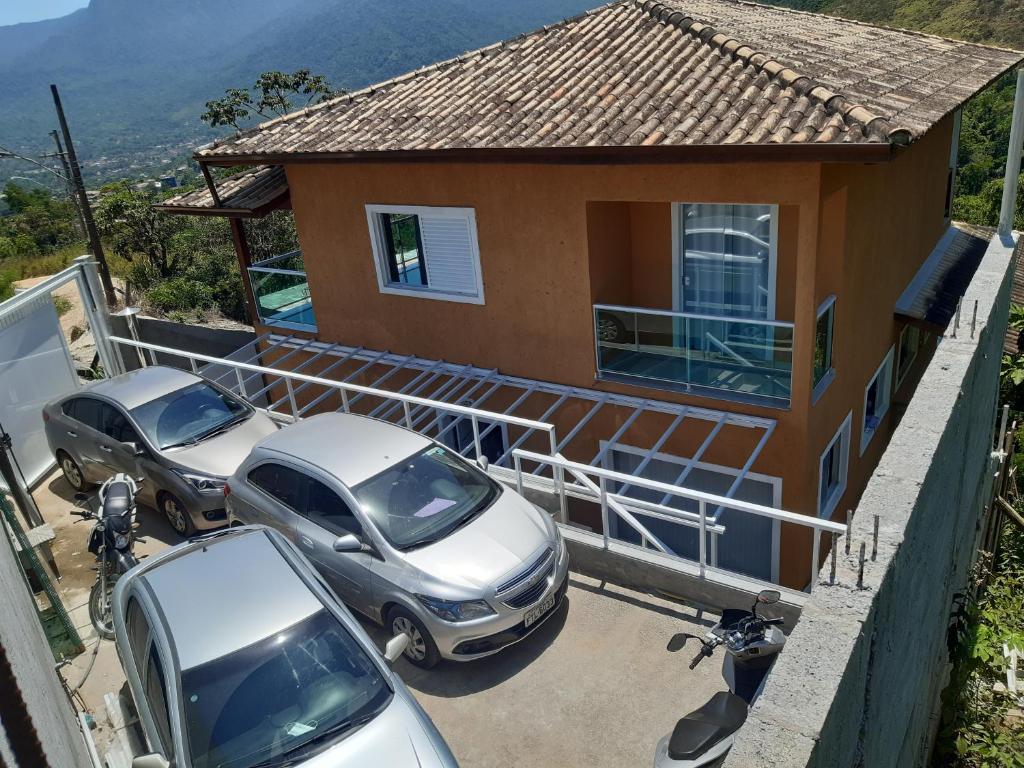 two cars parked in a parking lot in front of a house at Linda casa com vista pro mar!! in Ilhabela