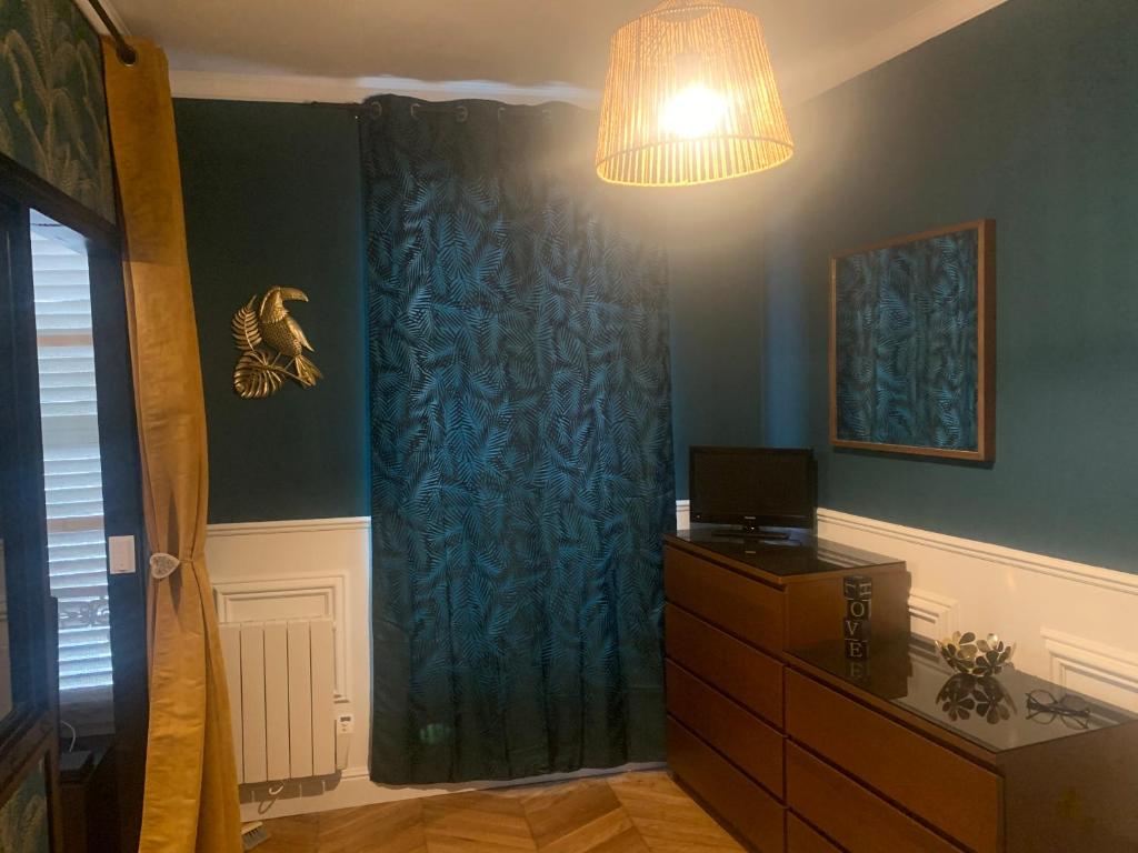 Pokój z niebieską zasłoną i komodą w obiekcie Appartement centre Fontainebleau w mieście Fontainebleau
