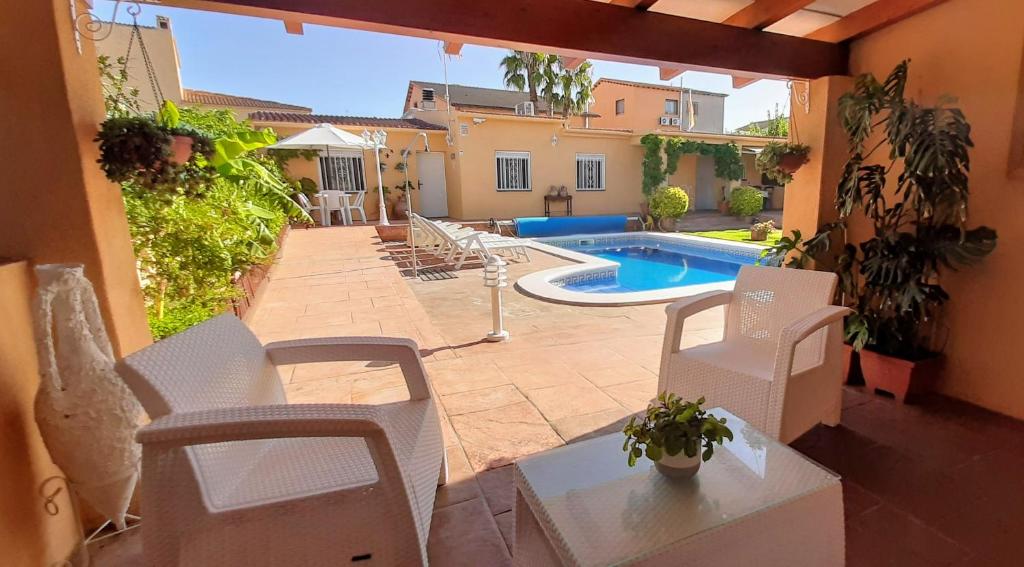 un patio con sillas blancas y una piscina en Chalet con piscina privada y barbacoa en Tarragona