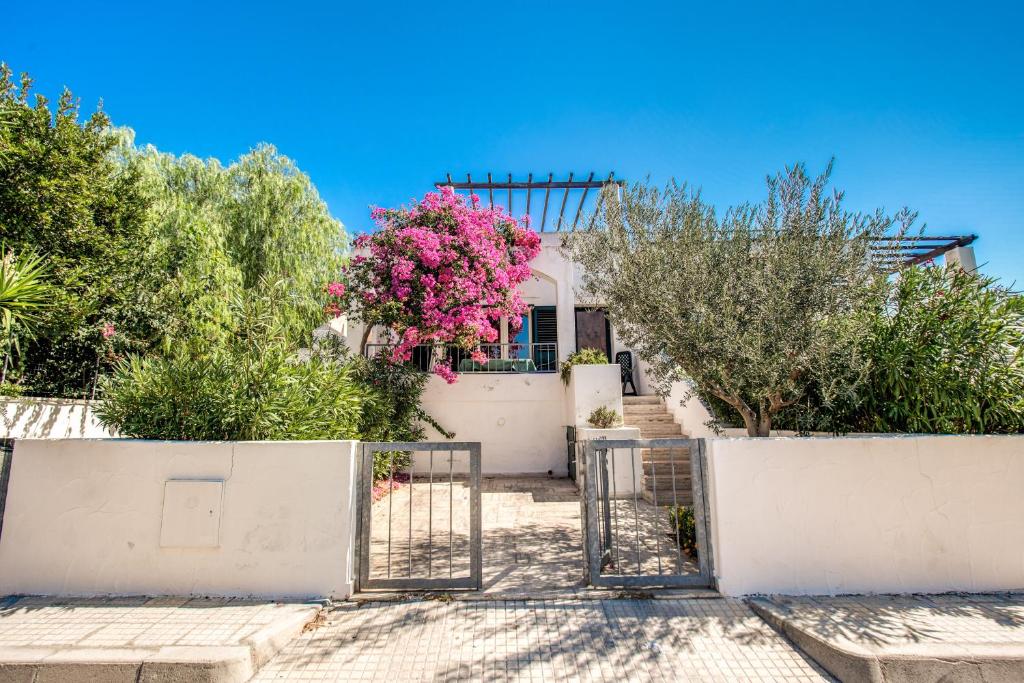una casa blanca con una puerta y flores rosas en La Casa della Stella Marina, en Marina di Mancaversa
