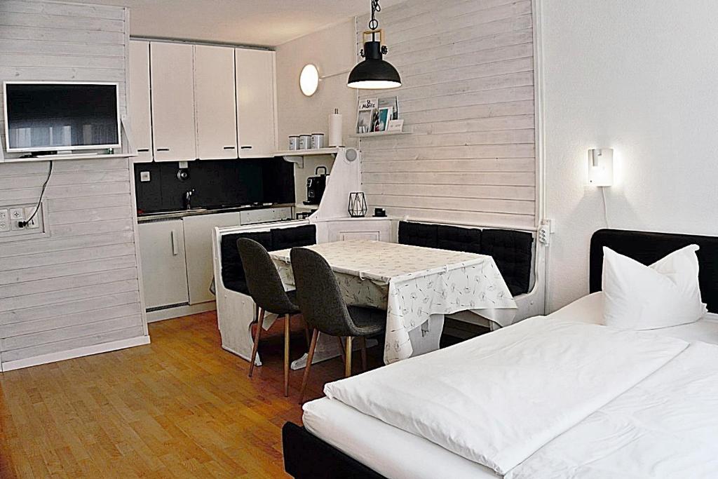 a bedroom with a bed and a table and a kitchen at Zentrale gemütliche Wohnung St Moritz - A212 in St. Moritz