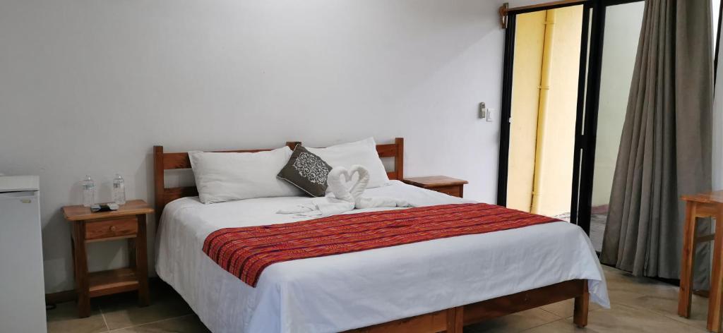 a bedroom with a white bed with a red blanket at Hotel Iker in Tulum