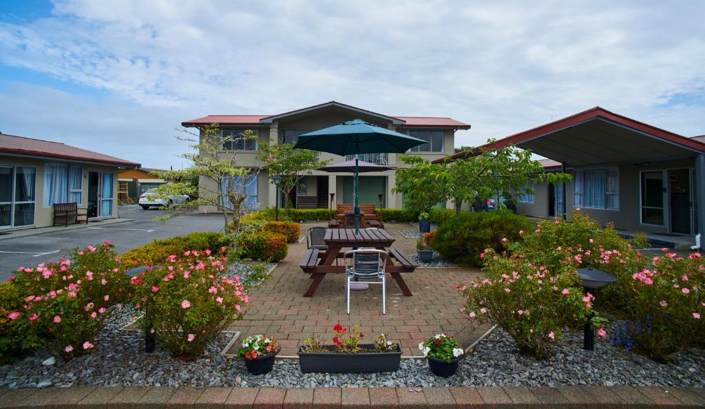a patio with benches and flowers in front of a building at Aachen Place Motel in Greymouth