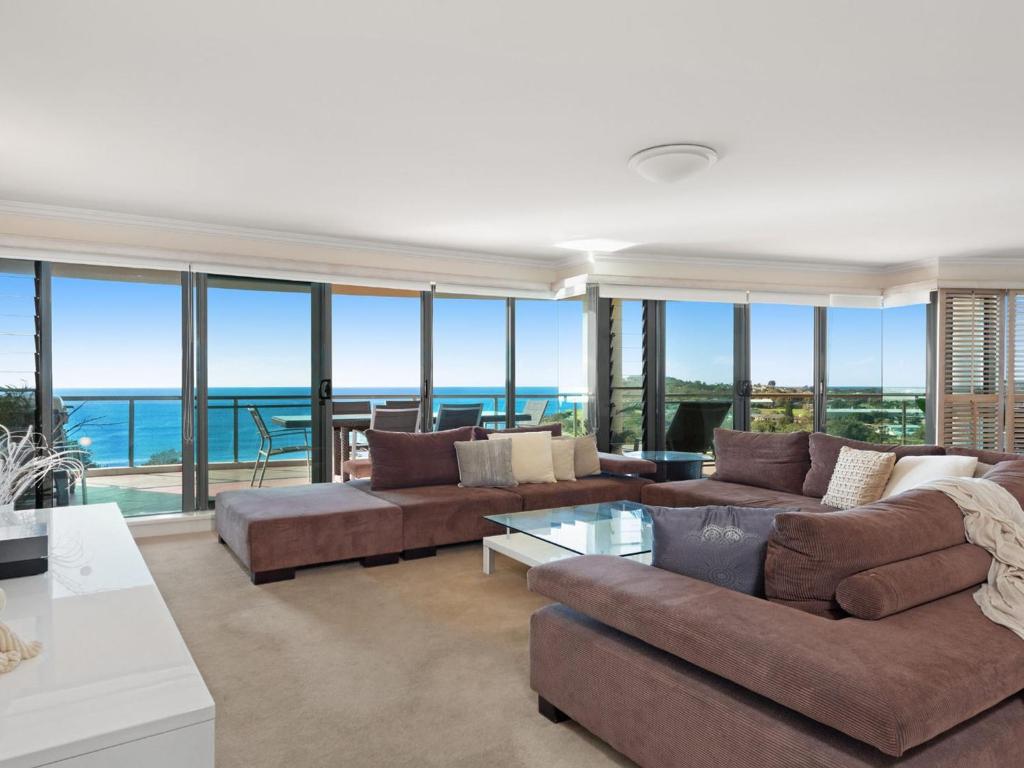 a living room with a large couch and glass windows at Le Point 702 Luxury and Views in Forster