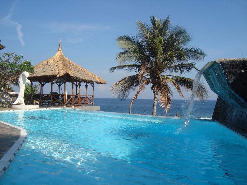 uma piscina com um gazebo junto ao oceano em Villa Arjuna em Seraya