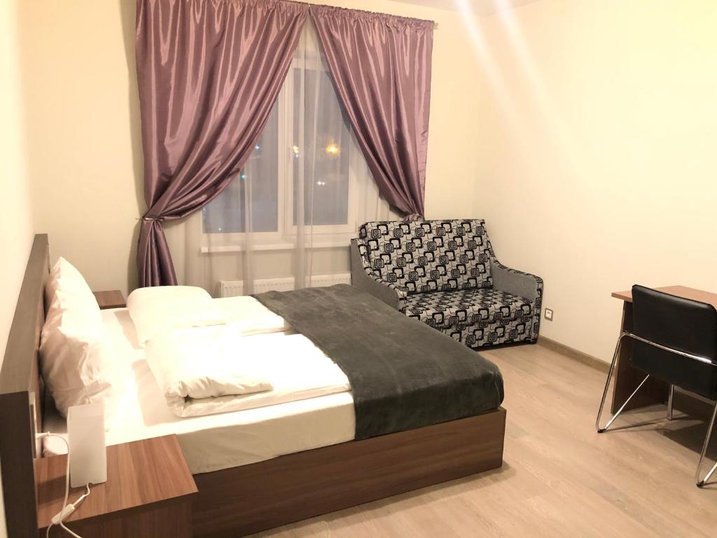 a bedroom with a bed and a chair and a window at Отель Лайнер in Khimki