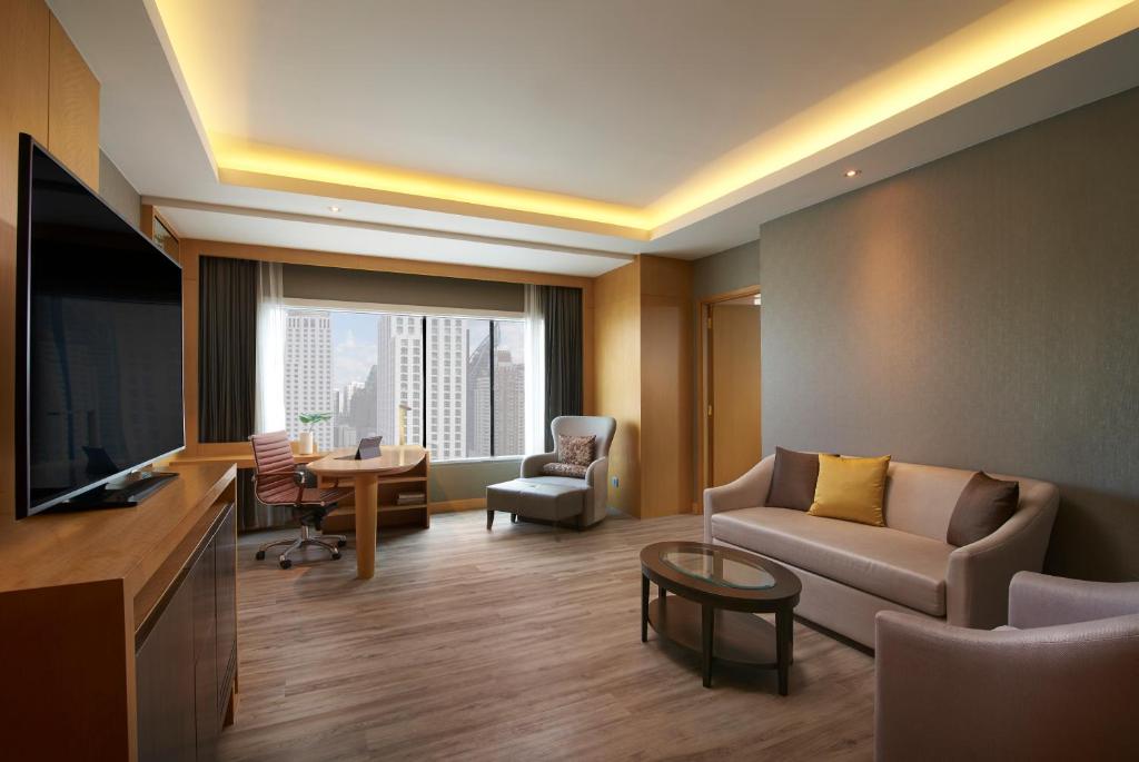a living room with a couch and a flat screen tv at Amari Bangkok in Bangkok