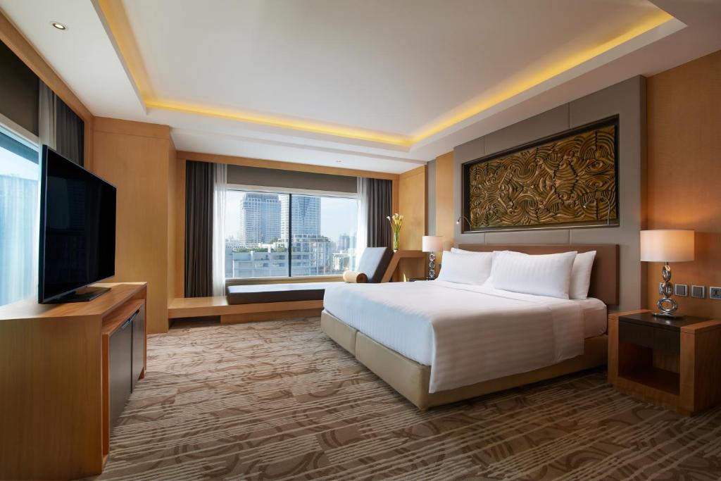 a hotel room with a bed and a flat screen tv at Amari Bangkok in Bangkok