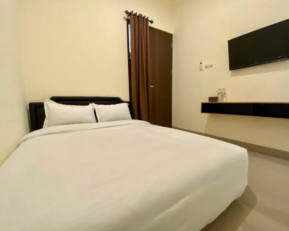 1 cama blanca grande en una habitación con TV en RedDoorz at Arkana Seturan Pakuwon Mall, en Yogyakarta