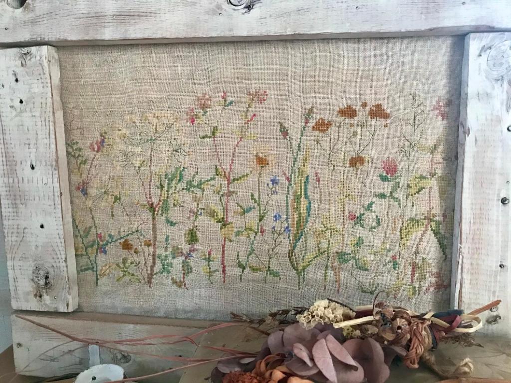 a tapestry hanging on a wall with flowers at Travelers House おーさんてぃん青空舎 in Taketomi
