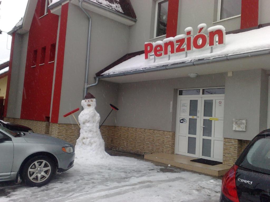 un muñeco de nieve parado frente a una gasolinera en Guest House Penzión Fortuna, en Tvrdošín