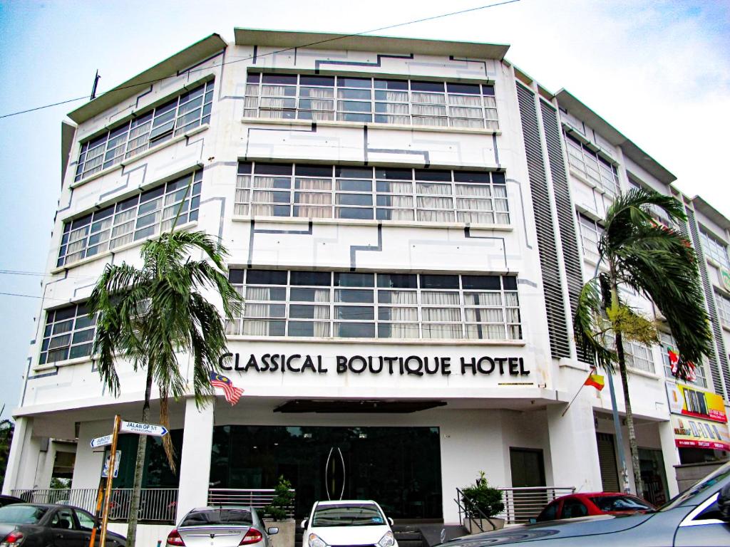a large white building with cars parked in front of it at Classical Boutique Hotel in Puchong
