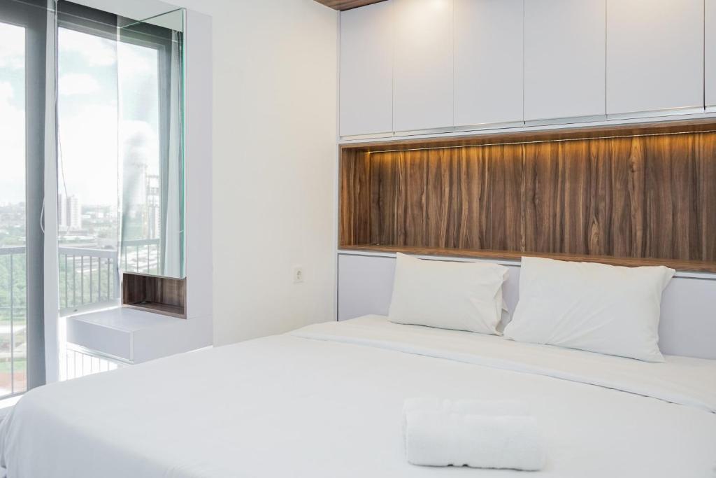 a bedroom with a white bed and a large window at Premium Relaxing 2BR at Casa de Parco Apartment By Travelio in Samporo