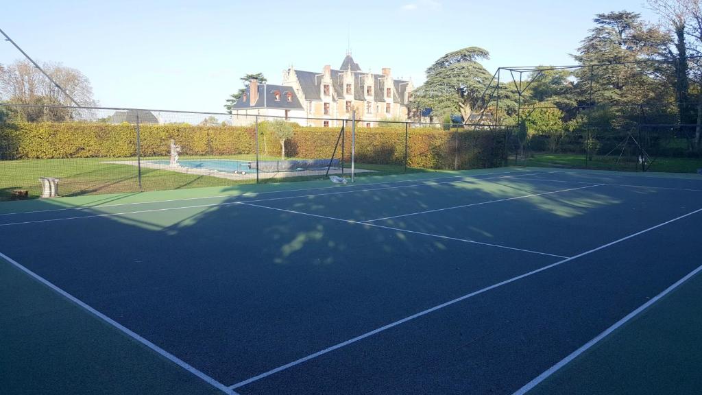 a tennis court with a building in the background at Demeure de 6 chambres avec piscine interieure jacuzzi et jardin clos a Vernou sur Brenne in Vernou-sur-Brenne