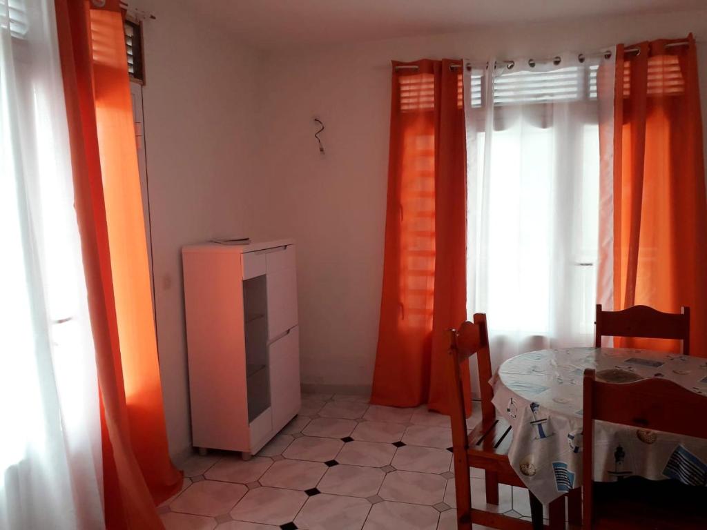 a room with orange curtains and a table and a table and chair at Maison de 3 chambres avec vue sur la mer terrasse et wifi a Vieux Habitants in Vieux-Habitants