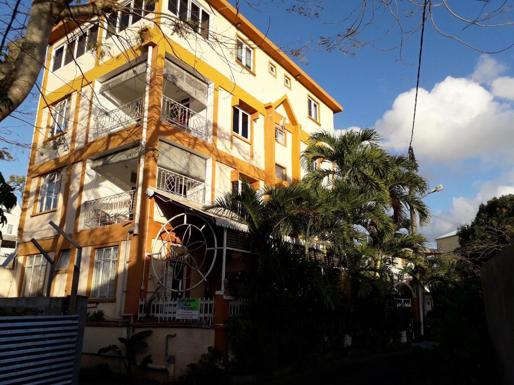 グランベにあるModern Apartment in Grand Bay, Balconyのヤシの木が目の前に広がる黄色い建物