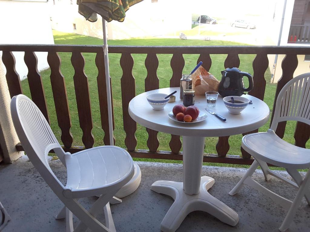 een witte tafel en stoelen op een balkon met fruit erop bij Appartement d'une chambre a Metabief a 400 m des pistes avec piscine interieure et balcon in Métabief