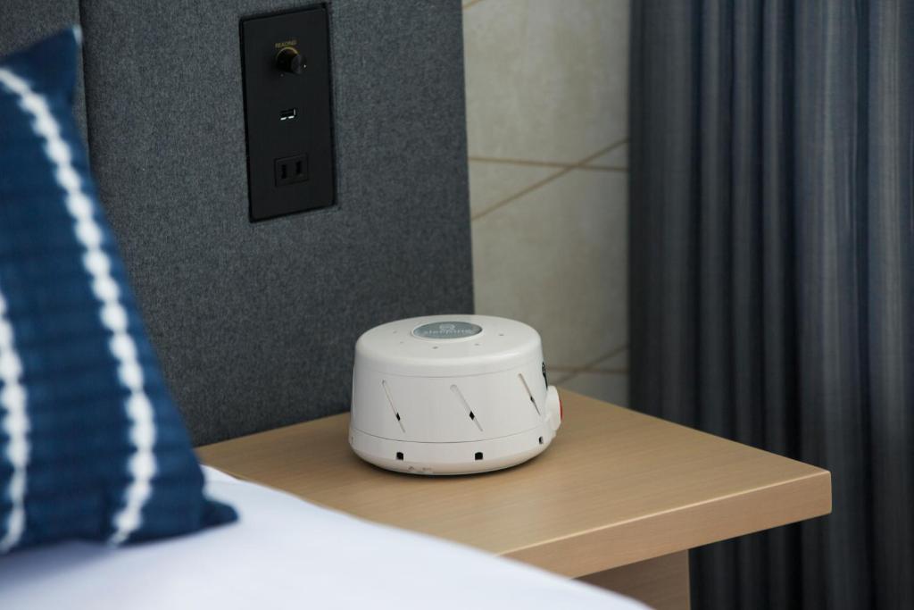 a alarm clock sitting on a table next to a bed at Nikko Style Nagoya in Nagoya