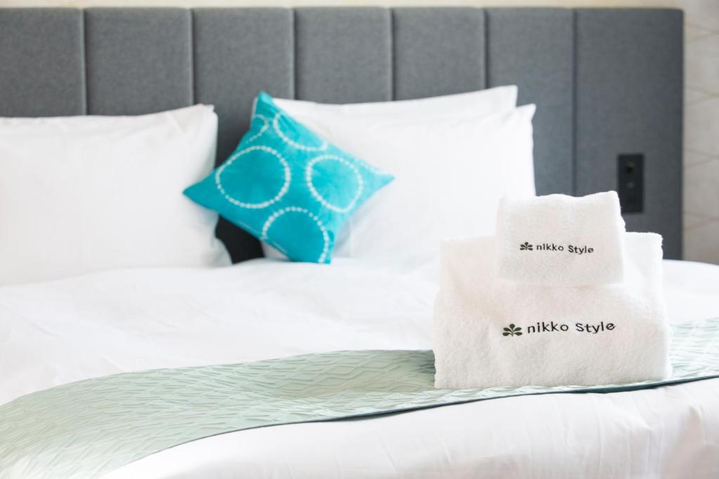 a bed with white pillows and a blue pillow at Nikko Style Nagoya in Nagoya