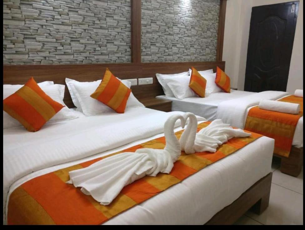 dos cisnes están sentados en dos camas en una habitación de hotel en HISHAM SUITES, en Ernakulam