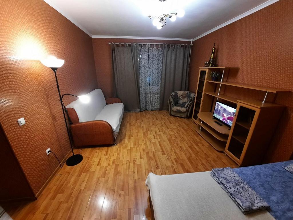 ウファにあるApartment Mustaya Karima 28のベッド、椅子、テレビが備わる客室です。
