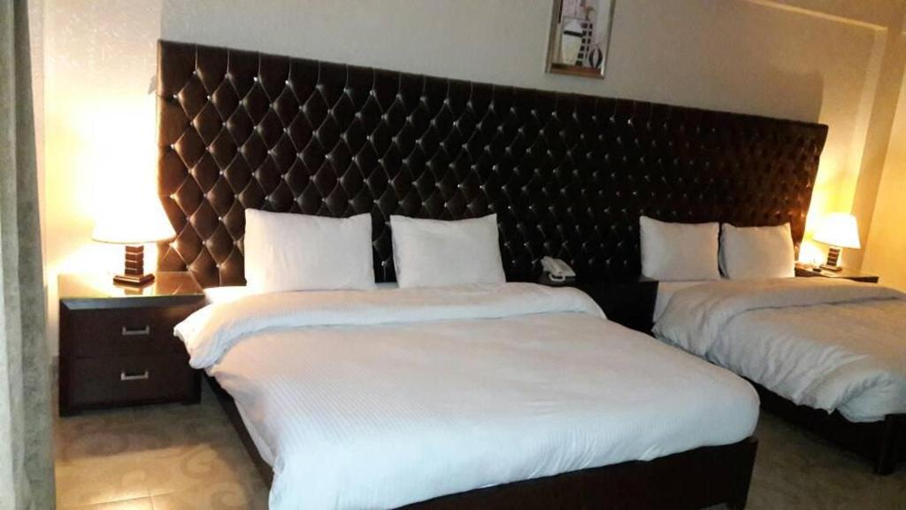 a hotel room with two beds and a large headboard at Millennium Inn Naran in Mānsehra