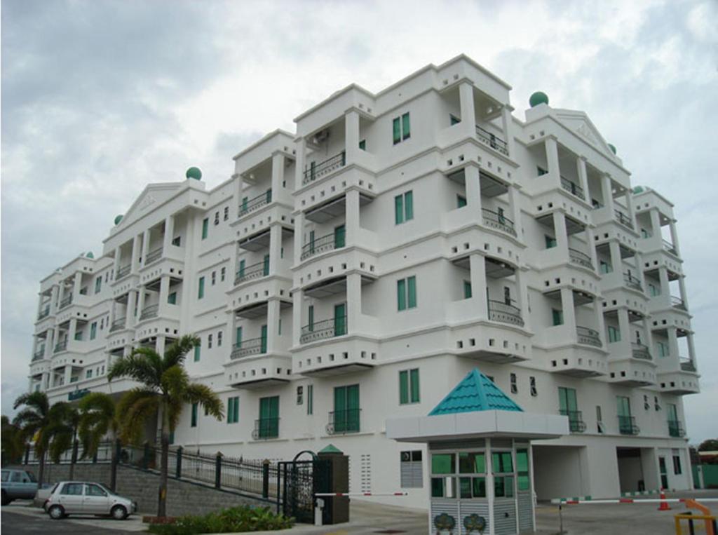 a large white building with a car parked in front of it at MCITI Suites in Miri