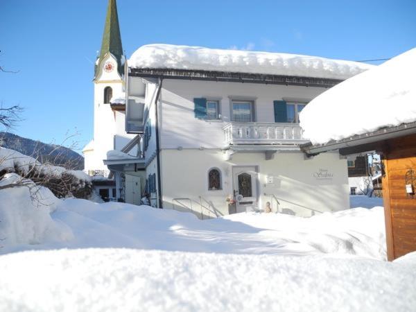 a house covered in snow with a church in the background at Haus Salina in Ellmau