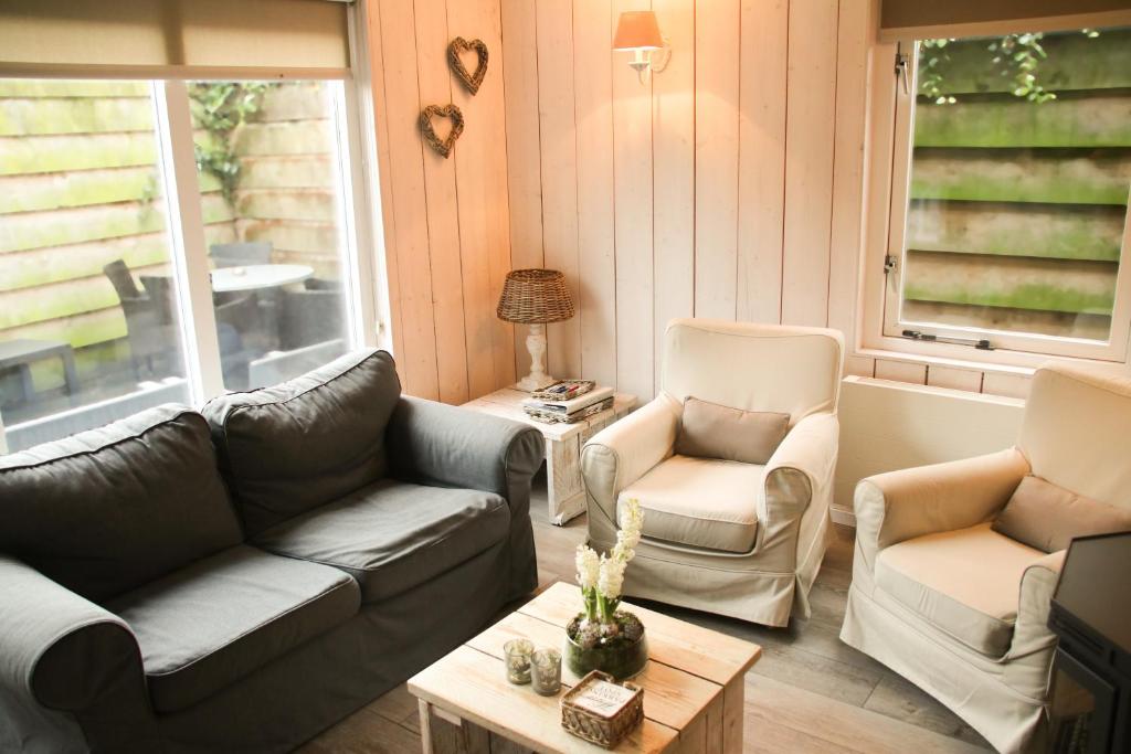 ein Wohnzimmer mit Sofas, Stühlen und einem Tisch in der Unterkunft Vakantiewoning Weverijstraat met strandcabine in Domburg