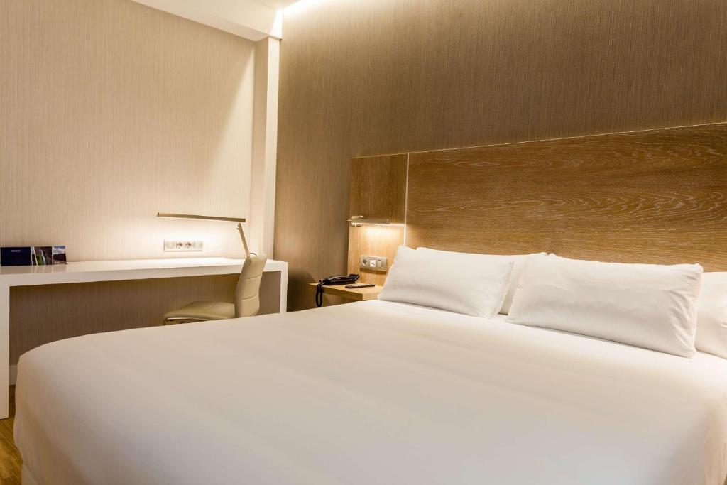 1 dormitorio con 1 cama blanca grande y escritorio en NH Oviedo Principado, en Oviedo