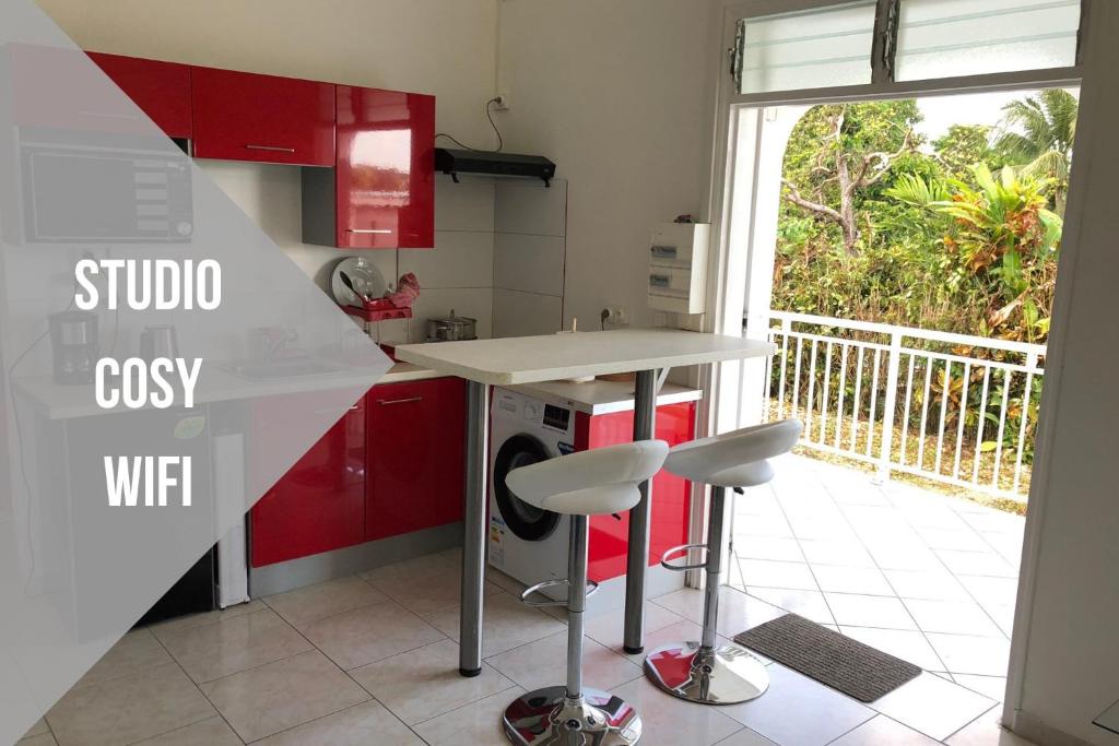 a kitchen with red cabinets and a counter with two stools at Sopraia Lodge in Les Abymes