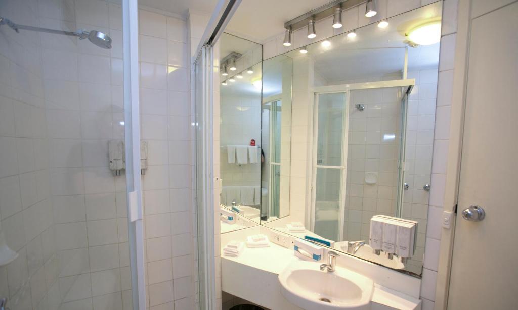 a bathroom with a sink, mirror, and shower at Madison Tower Mill Hotel in Brisbane