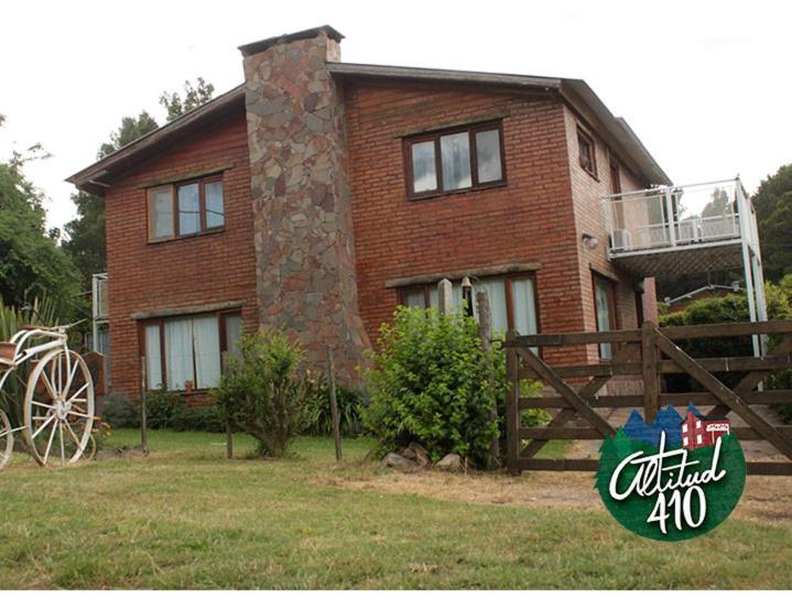 una casa de ladrillo con una valla de madera delante de ella en Altitud 410 en Villa Ventana