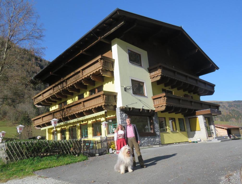 dos personas y un perro delante de un edificio en Alpenhaus Denver en Uttendorf