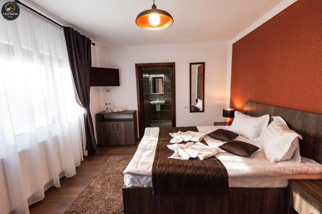 a bedroom with a large bed with white sheets at Casa Raisa in Buşteni