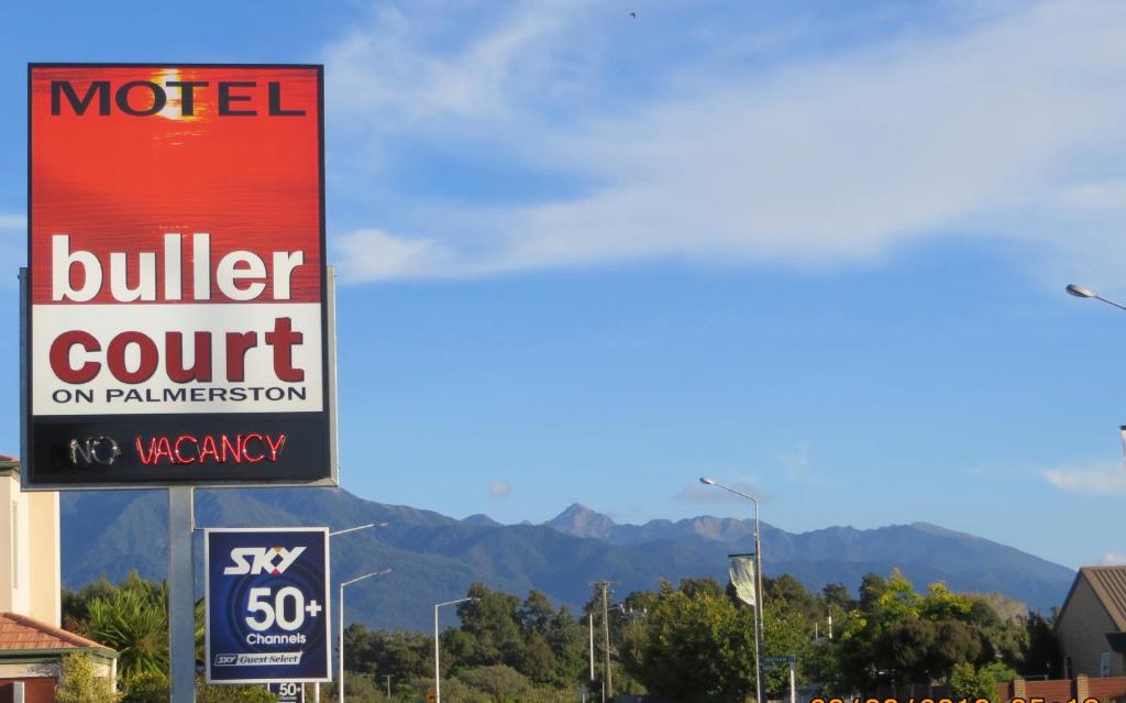 a sign for a motel cullier court with mountains in the background at Buller Court on Palmerston in Westport