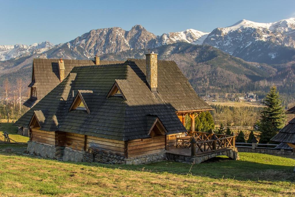 a log cabin with mountains in the background at Dom Markówka Zakopane in Kościelisko