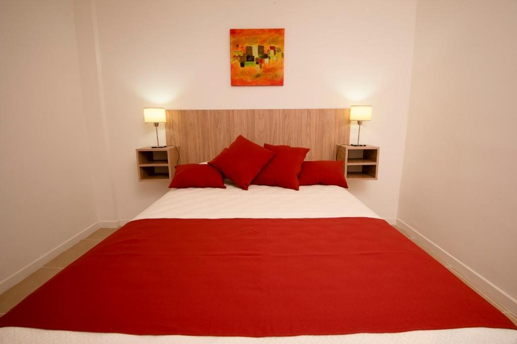 Un dormitorio con una cama roja y blanca con almohadas rojas en Edificio Paseo del Sol en Necochea