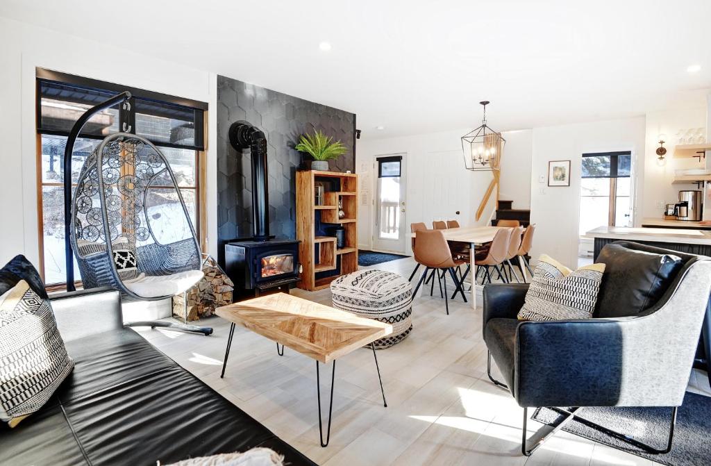 Una sala de estar con chimenea y una mesa. en Chalets Alpins - 14 Chemin Alpin, en Stoneham