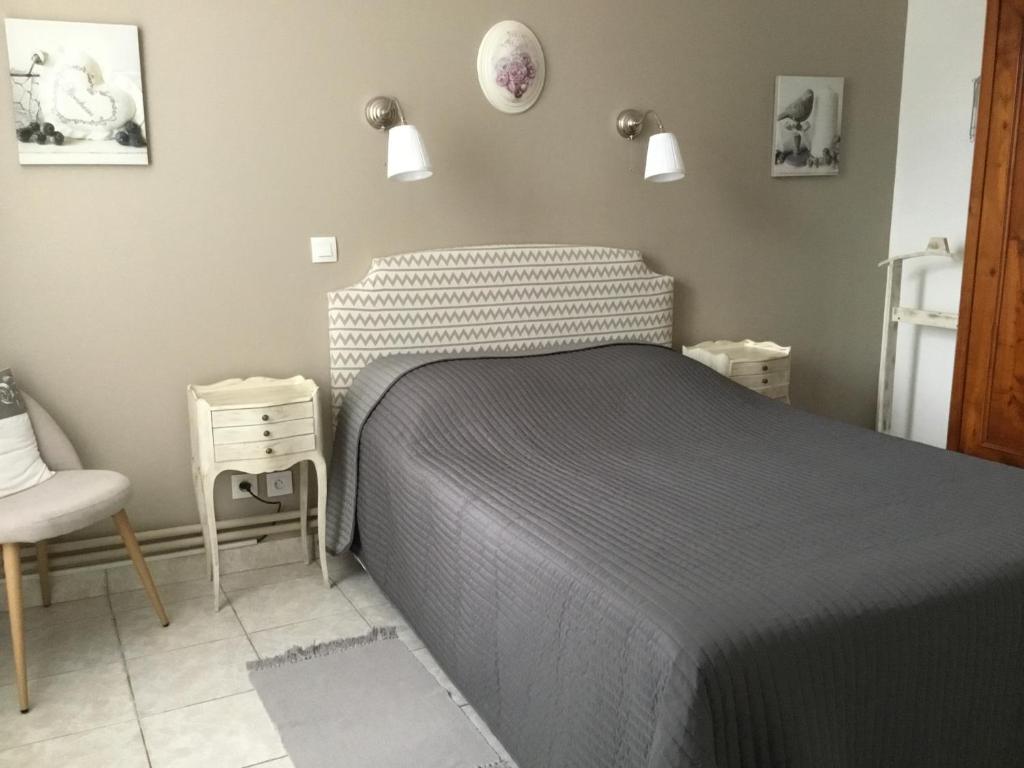 a bedroom with a bed and a chair at le gite de la CURE in Pessac-sur-Dordogne