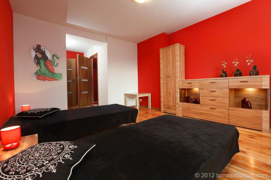 1 dormitorio con 2 camas y pared roja en Hotelik Bach, en Gdansk